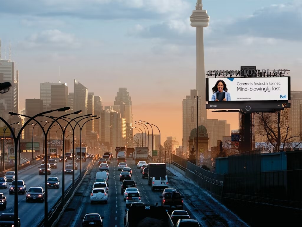 Biển quảng cáo ngoài trời tấm lớn đặt bên đường cao tốc với nhiều phương tiện giao thông qua lại trong khu đô thị.