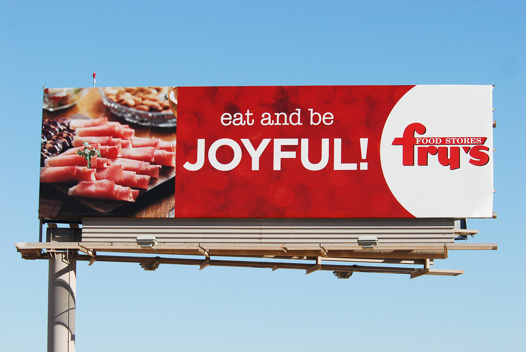 #11. Biển quảng cáo của Fry's Food Stores với nền đỏ nổi bật, hình món ăn hấp dẫn và thông điệp “Eat and be joyful!”.