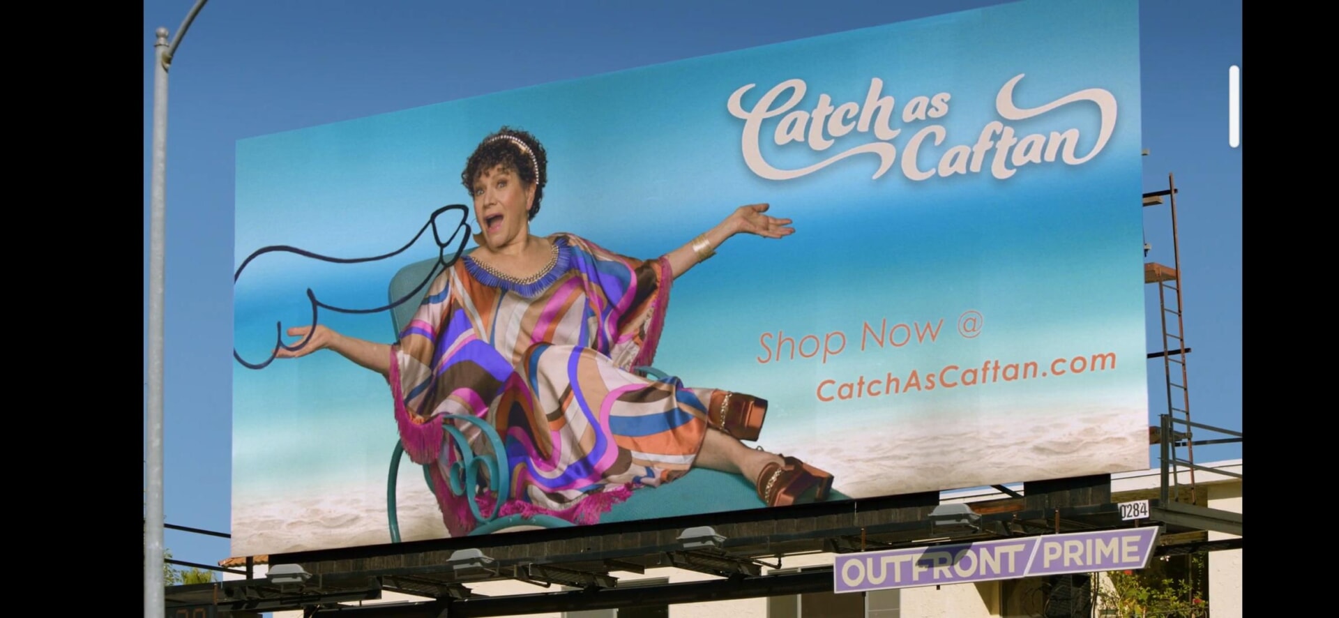 Biển billboard quảng cáo thời trang “Catch as Caftan” với hình ảnh người phụ nữ tạo dáng vui nhộn