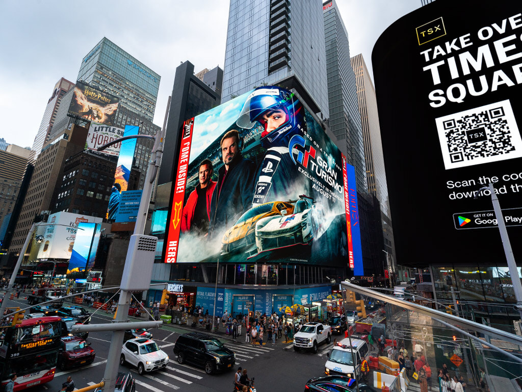 #93. Biển quảng cáo LED khổng lồ tại quảng trường nhộn nhịp hiển thị phim Gran Turismo với hình ảnh xe đua tốc độ cao, thu hút ánh nhìn giữa không gian đô thị hiện đại.